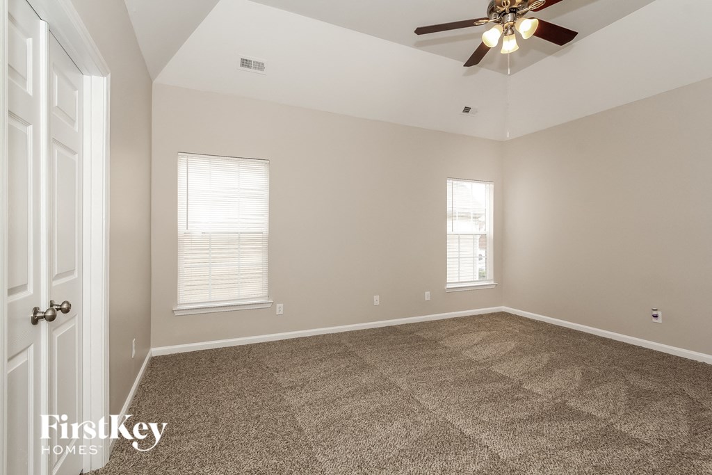 a empty living room with carpet and a ceiling fan