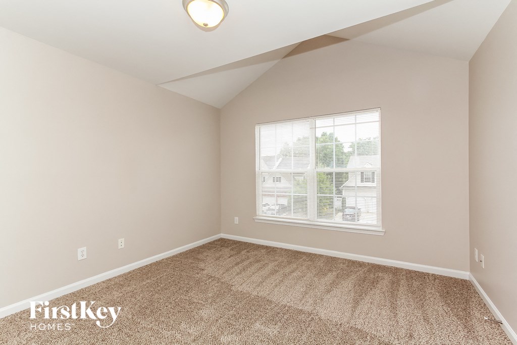 the second bedroom is spacious and has carpeting and a large window