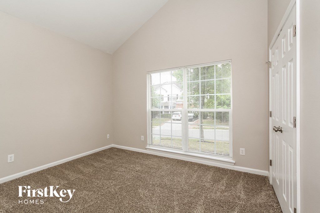 the second bedroom has a large window and carpeted flooring