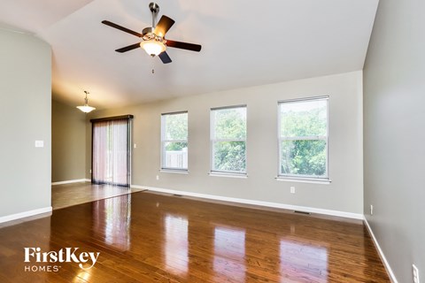 an empty living room with wood floors and a ceiling fan