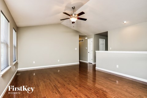an empty living room with wood floors and a ceiling fan