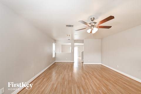 A spacious room with a ceiling fan and wooden flooring.