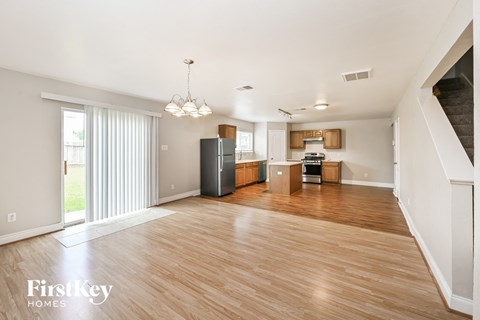 A spacious living room with wooden floors and a staircase on the right.