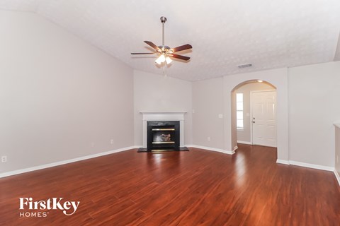 A spacious room with a fireplace and a ceiling fan.