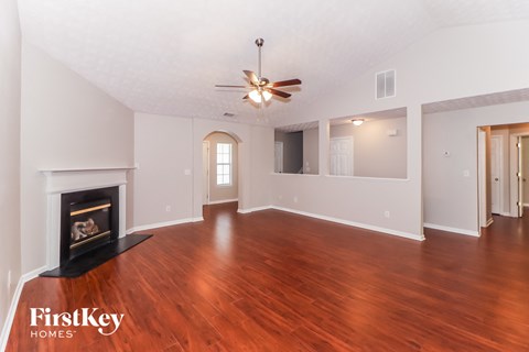 A spacious room with a fireplace and wood flooring.