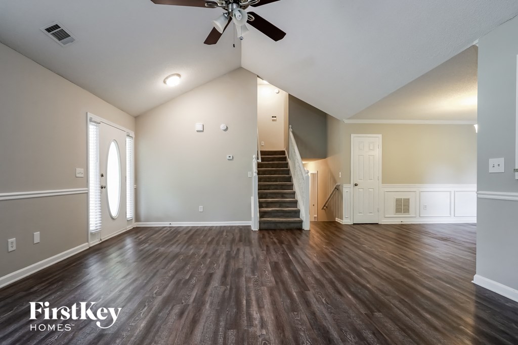 an empty living room with wood floors and a ceiling fan