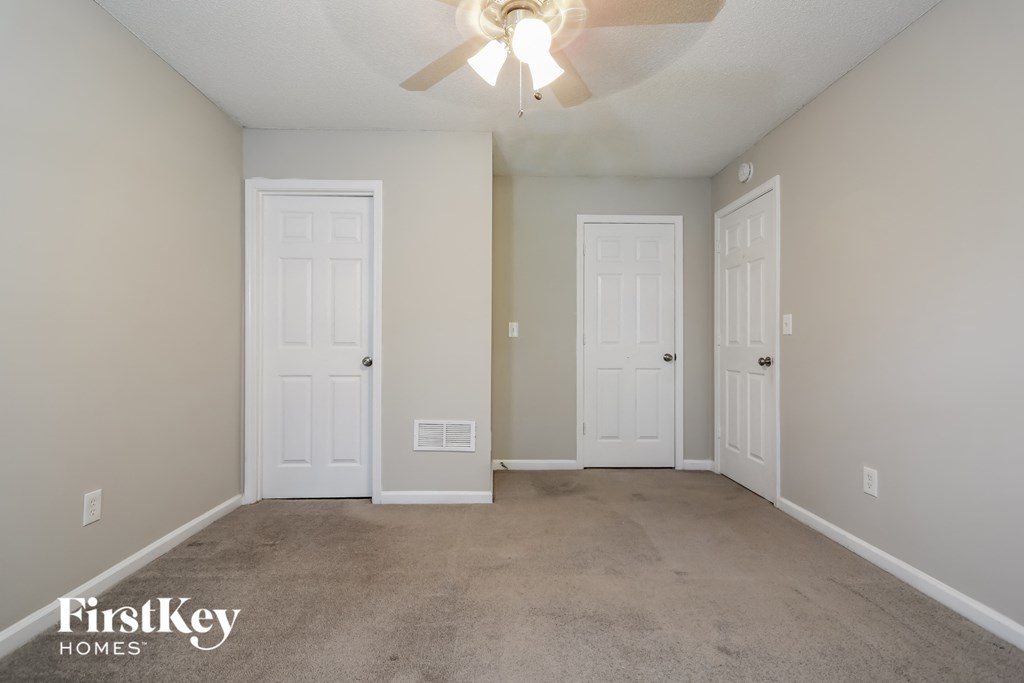 a empty living room with two doors and a ceiling fan