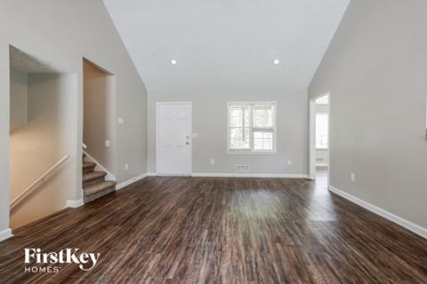the living room and entryway of a new home with wood floors and white walls