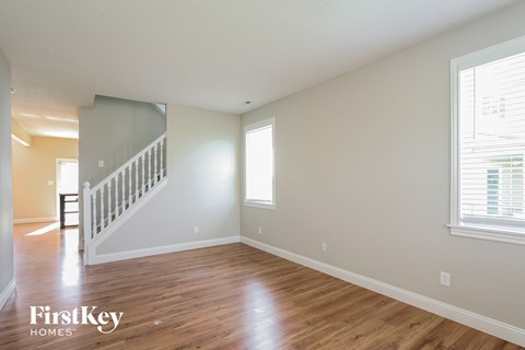 A spacious room with wooden floors and a staircase leading to another level.