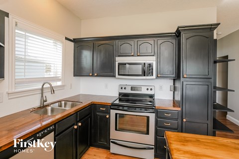 A kitchen with black cabinets and a stove top oven.