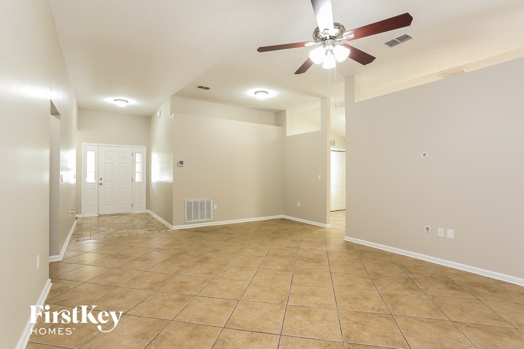 the spacious living room with ceiling fan and tile flooring