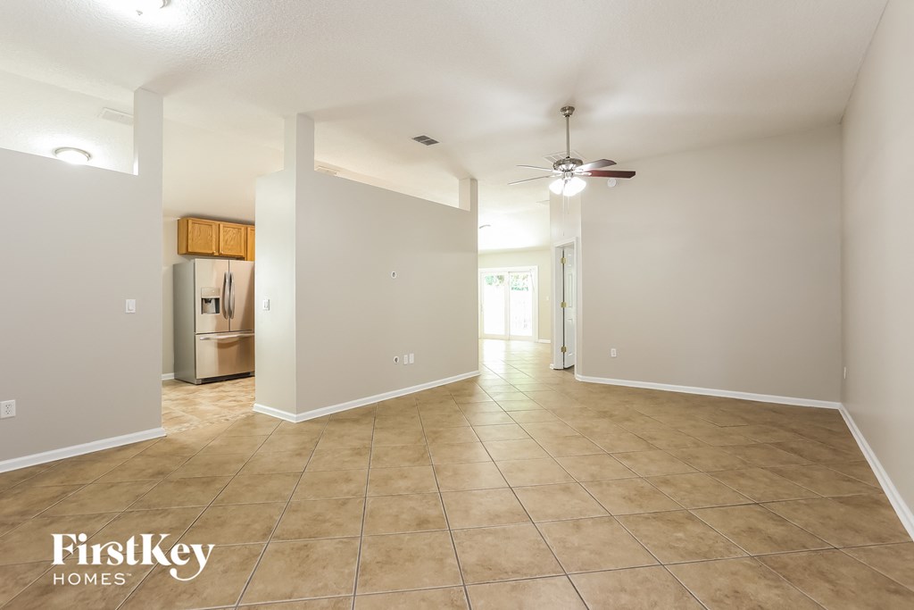 the spacious living room and kitchen with tile flooring and a ceiling fan