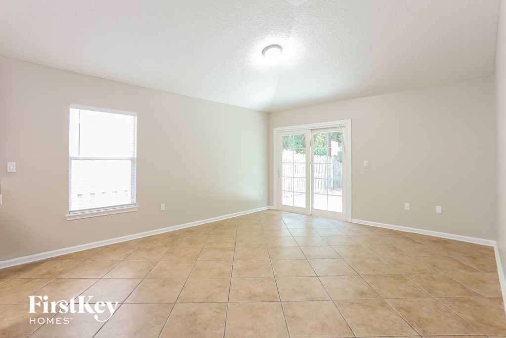 a spacious living room with tile flooring and a door to a patio