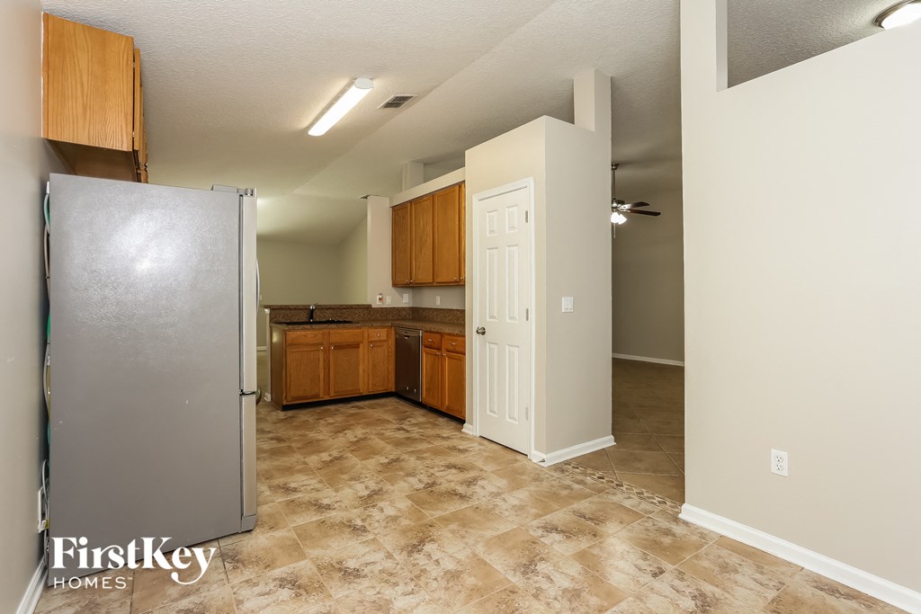 a kitchen with a refrigerator and wooden cabinets