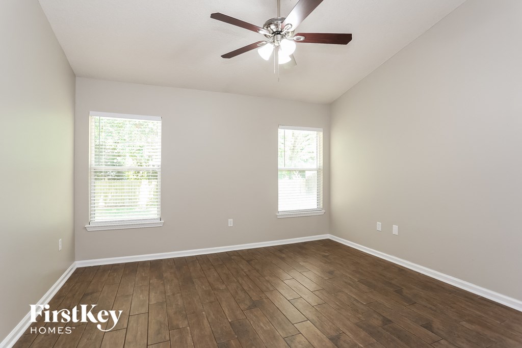 the spacious living room with hardwood floors and a ceiling fan