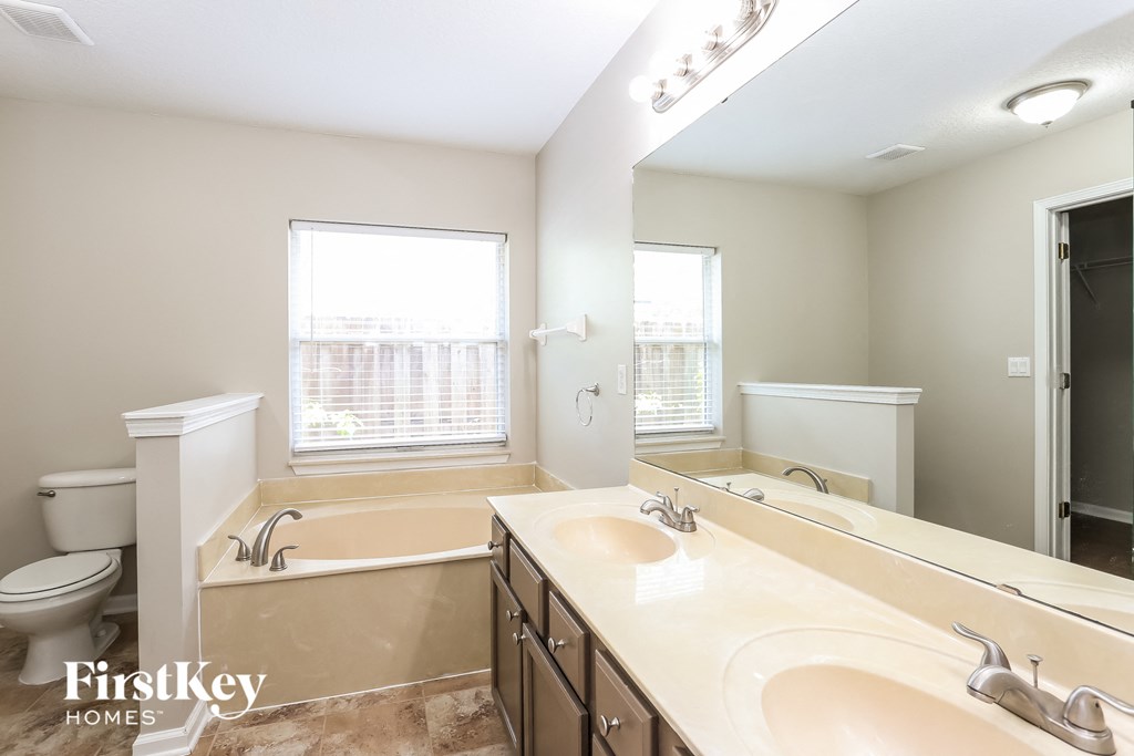 a bathroom with two sinks and a tub and a toilet