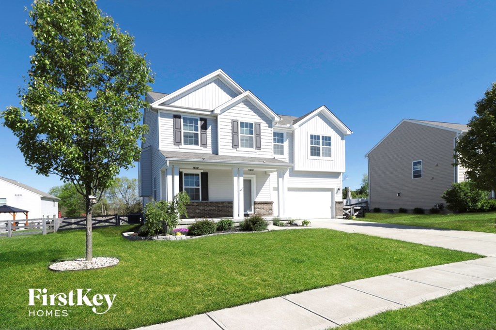 a white house with a lawn and a tree