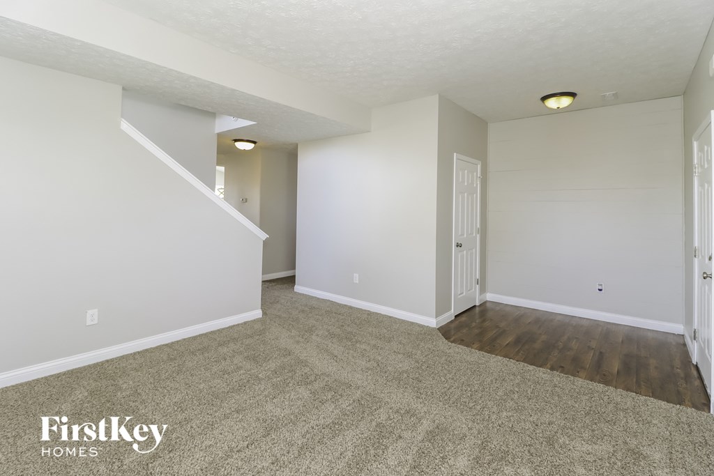 a spacious living room with white walls and wood flooring