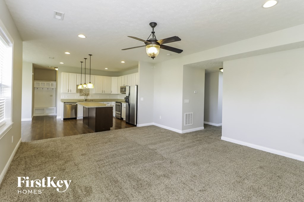 an empty living room and kitchen with a ceiling fan