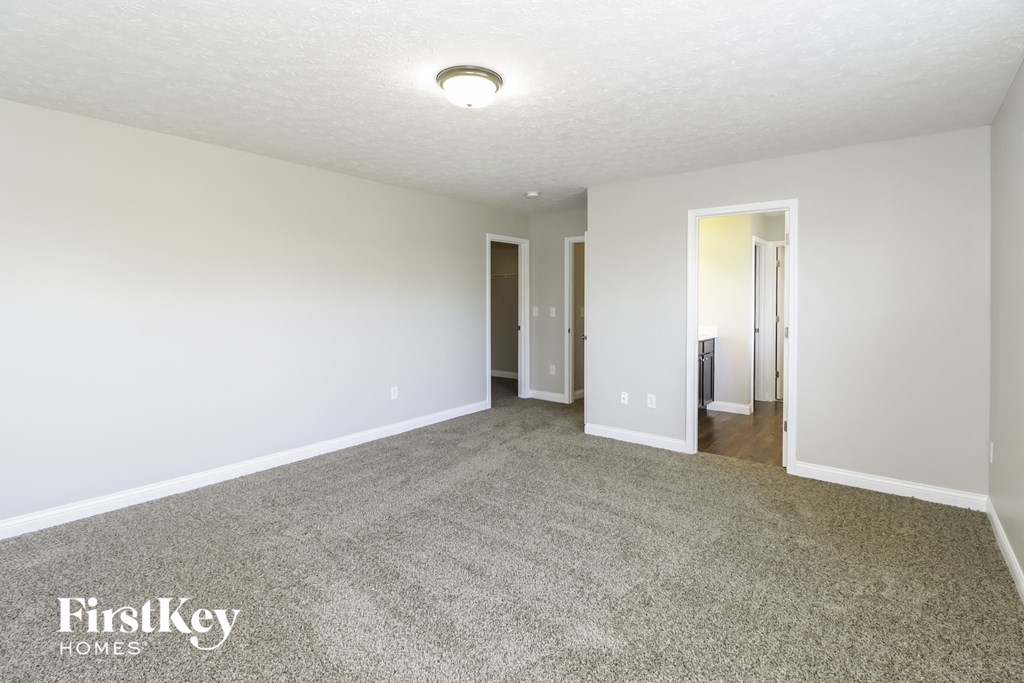 a spacious living room with carpet and white walls