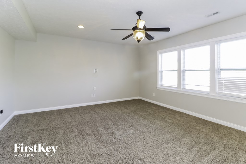 an empty living room with a ceiling fan and two windows