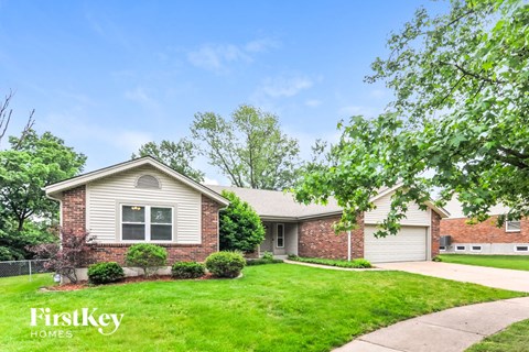 A house with a well-maintained lawn and trees in the background.