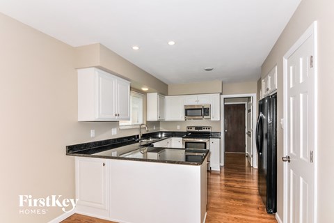 A kitchen with white cabinets and black countertops.