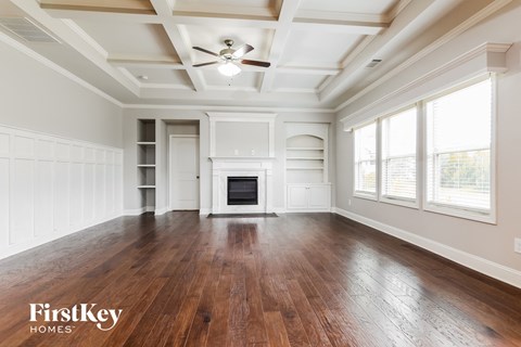 A spacious room with wooden floors and a fireplace.