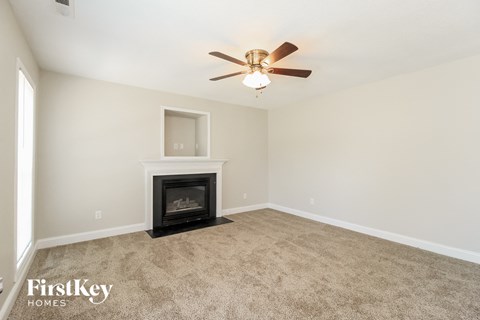A living room with a fireplace and a ceiling fan.