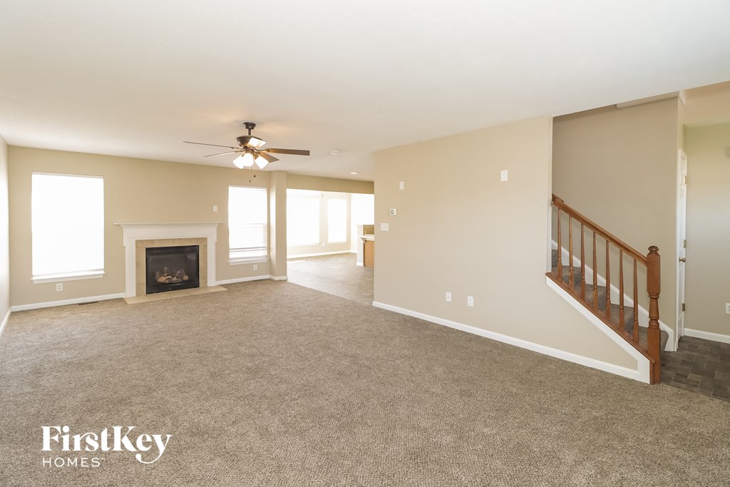 an empty living room with a fireplace and a staircase