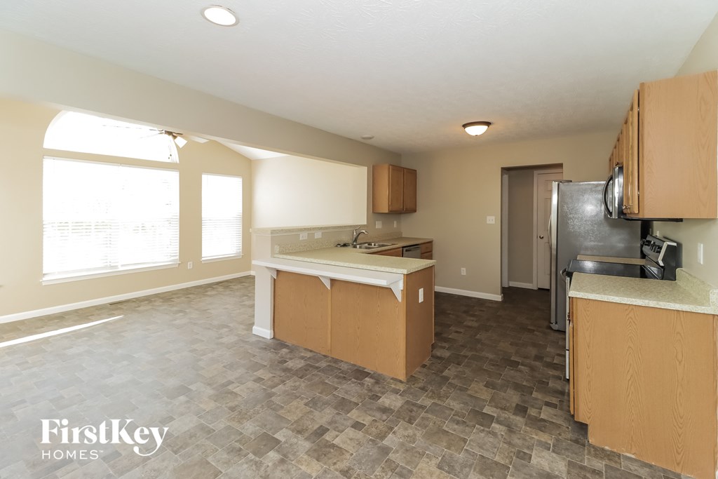 an empty kitchen with wood cabinets and a large window