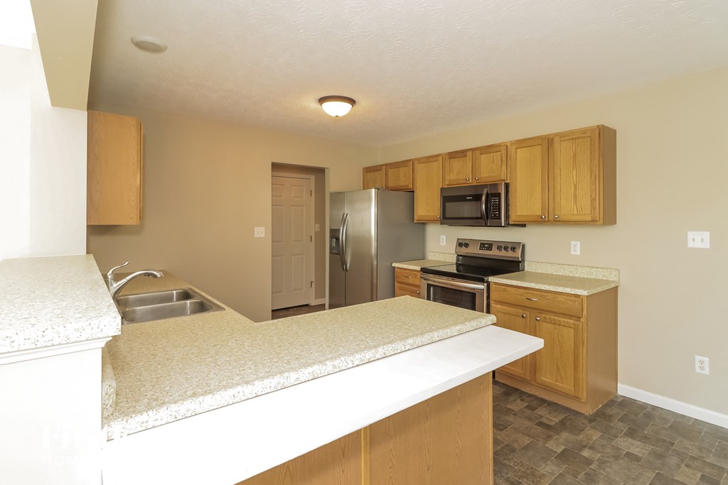 a kitchen with an island and a stainless steel refrigerator