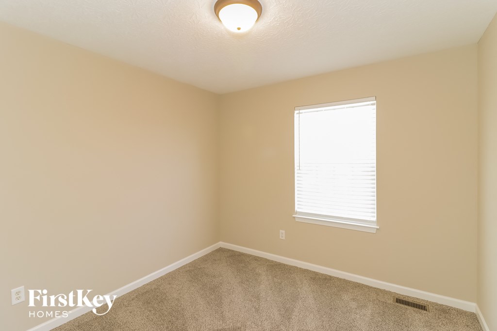 a bedroom with a window and a carpeted floor