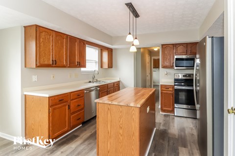 A kitchen with wooden cabinets and a wooden island.