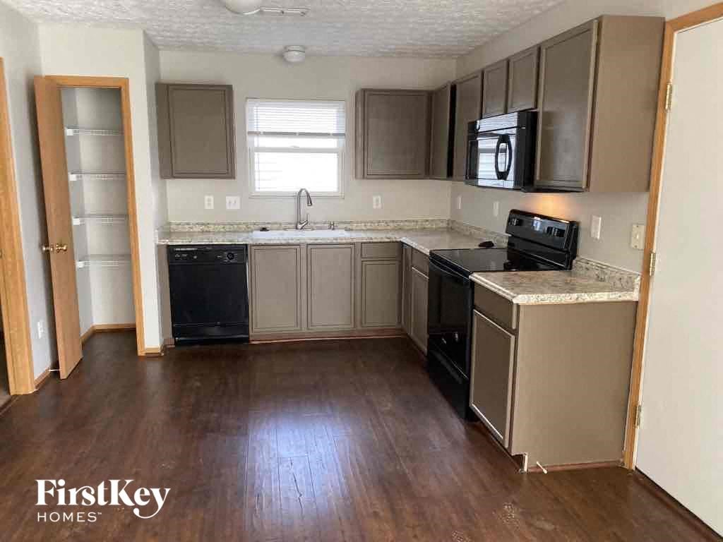 an empty kitchen with wooden floors and stainless steel appliances