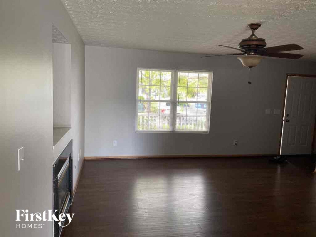 an empty living room with a ceiling fan and a window