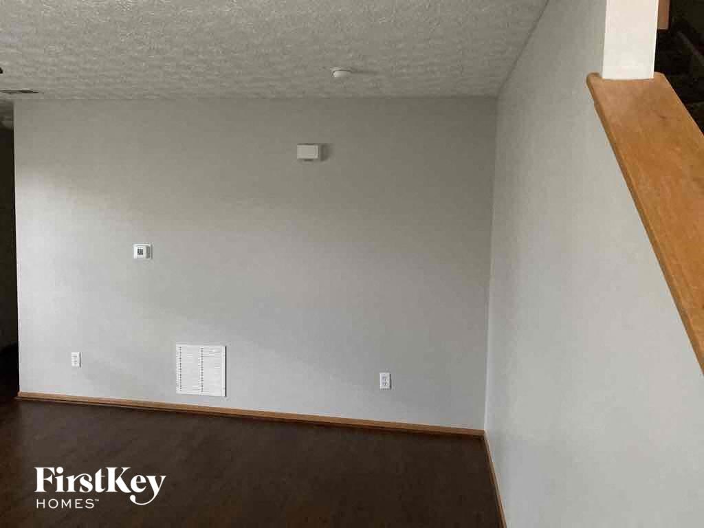 an empty room with white walls and a wooden staircase