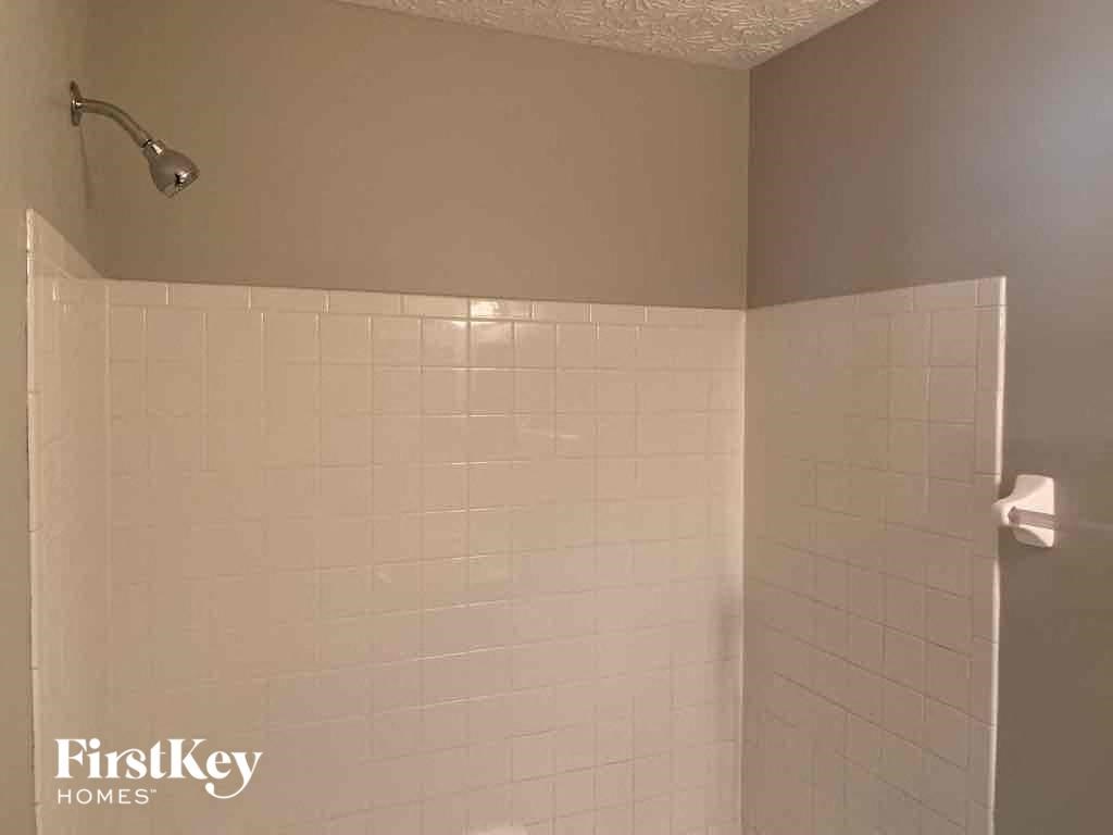 a bathroom with a shower and a white tiled wall