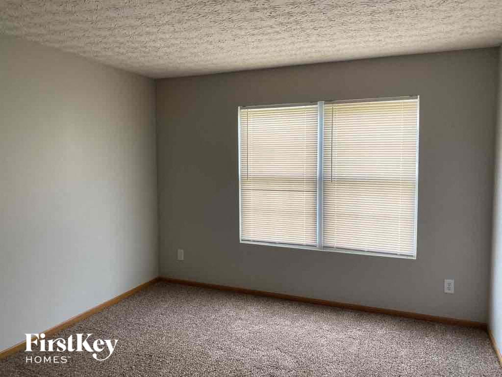 a bedroom with a window and a carpeted floor