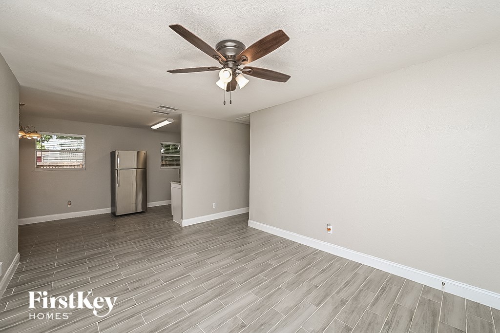 a living room with a ceiling fan and a refrigerator