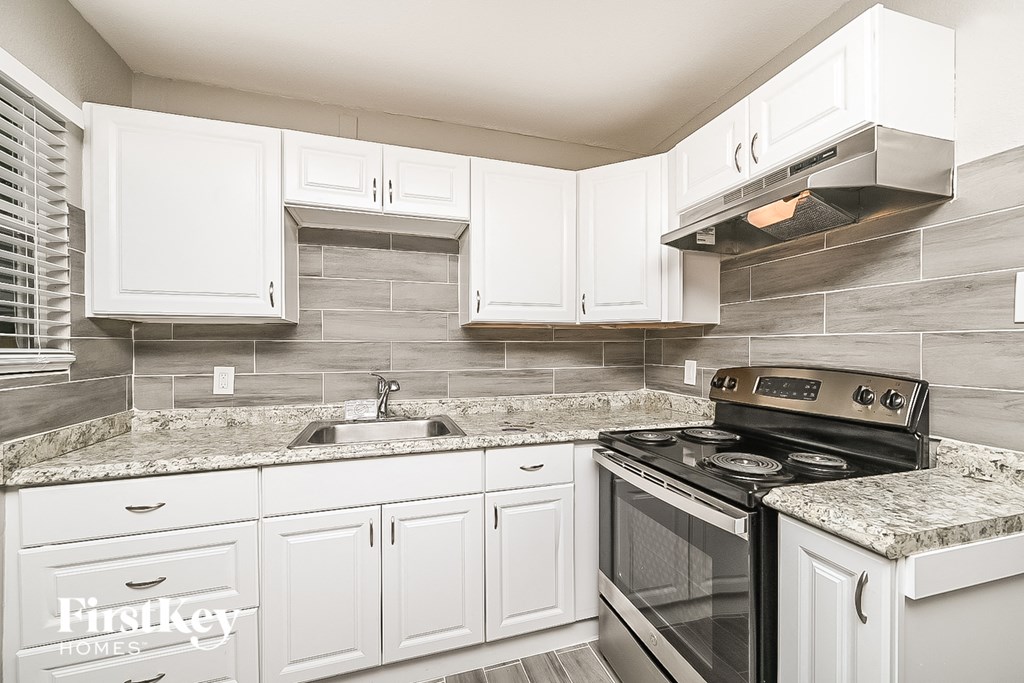 a white kitchen with white cabinets and a black stove