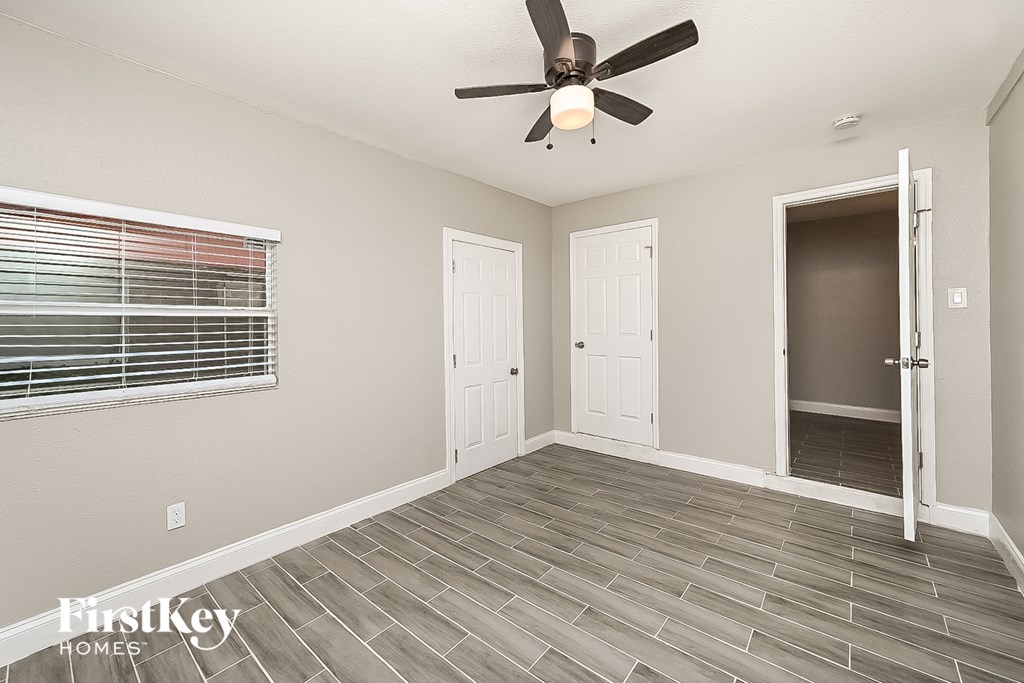 the living room of a home with a ceiling fan and a door to the hallway
