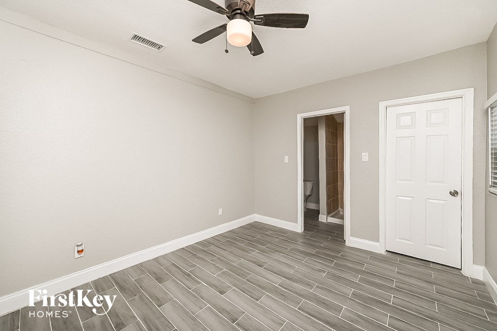 a living room with a ceiling fan and a door to a bathroom