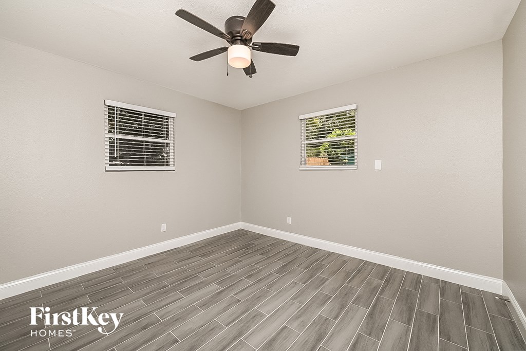 the spacious living room has a ceiling fan and wood floors