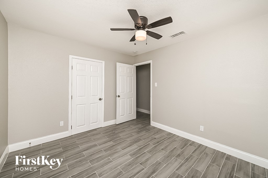 a living room with a ceiling fan and a door to a closet