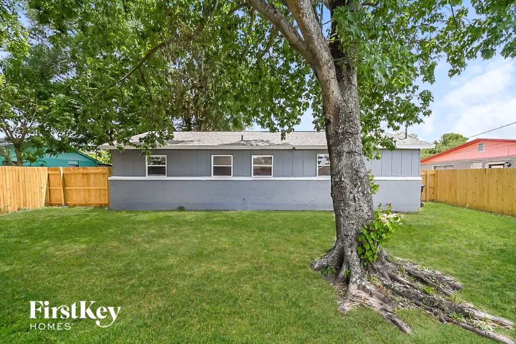a backyard with a tree and a gray house