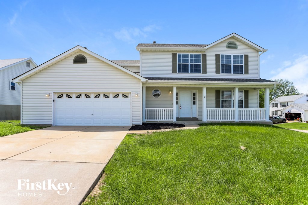 a white house with a white garage door and a lawn