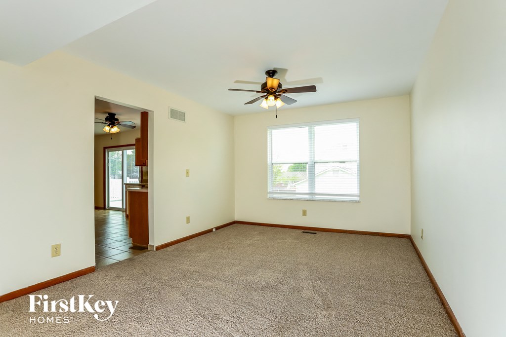 an empty living room with a ceiling fan and a window