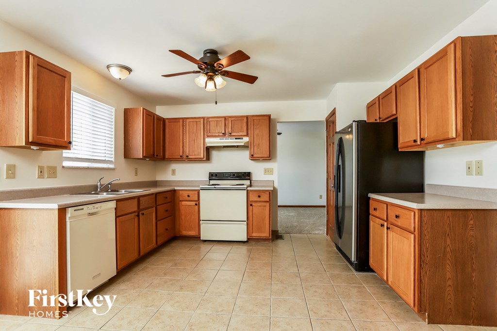 a kitchen with wooden cabinets and white appliances and a ceiling fan