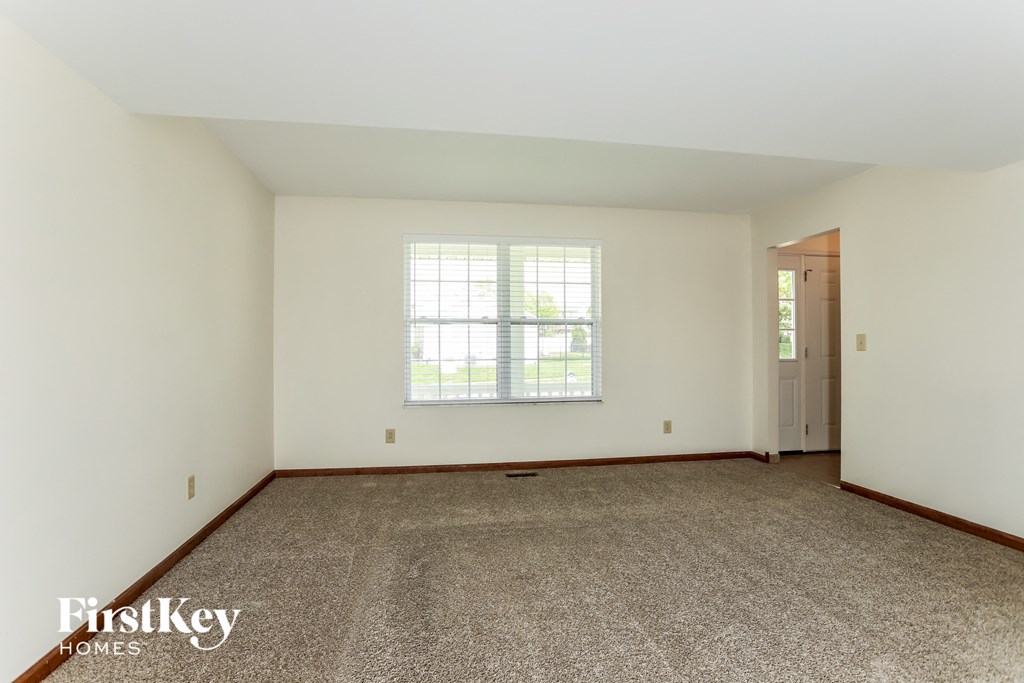 a master bedroom with carpet and white walls and a window